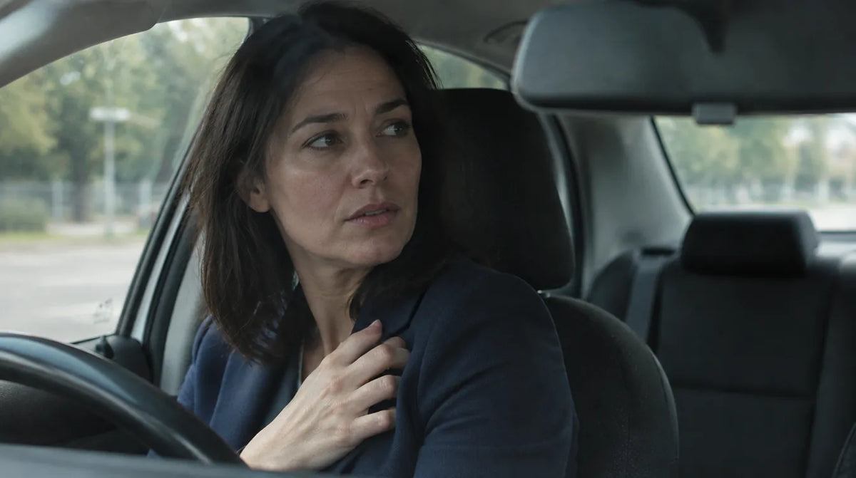 Woman in a navy blazer in her parked car, glancing over her shoulder with a worried look before a meeting, a common moment for anyone looking for dandruff treatment