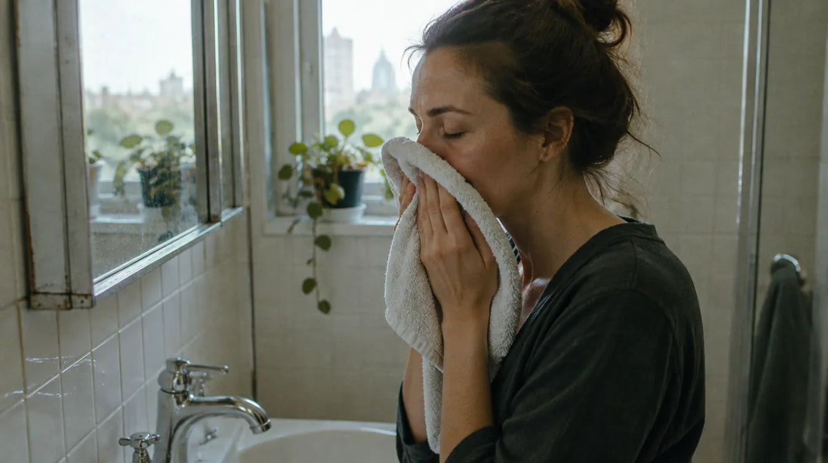 Australian woman patting her face dry with a towel after rinsing off a clay mask, illustrating how often should you use a clay mask