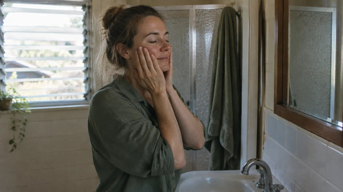 Australian woman at a bathroom basin in morning light, calm after finishing her skincare routine order