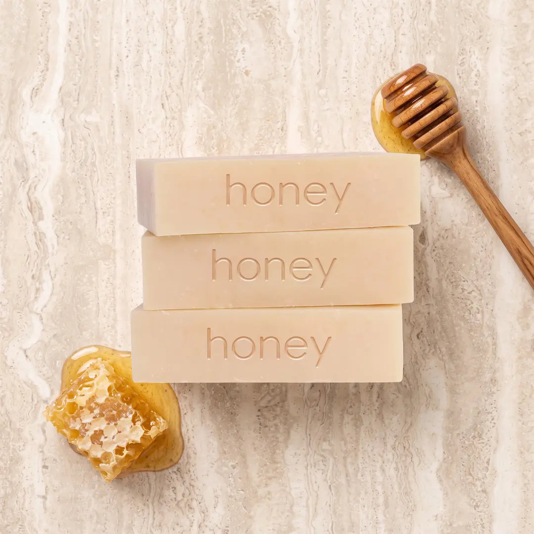 Luxury flatlay of Tasic Pure Oils Manuka Honey Soap bars styled with raw honeycomb and a wooden honey dipper