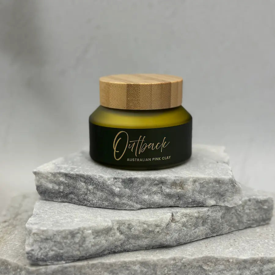 Jar of Outback Australian Pink Clay on a stone surface with a gray background