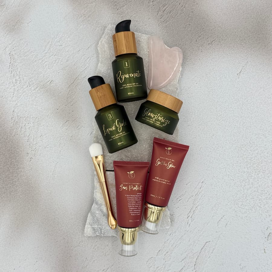 Tasic Pure Oils Exfoljenate skincare bundle flatlay featuring Rejuvenate rosehip oil, Liquid Gold argan oil, Glowsturize exfoliator, Sun Protect SPF50+ and Go for Glow night repair, styled with a rose quartz gua sha and makeup brush

