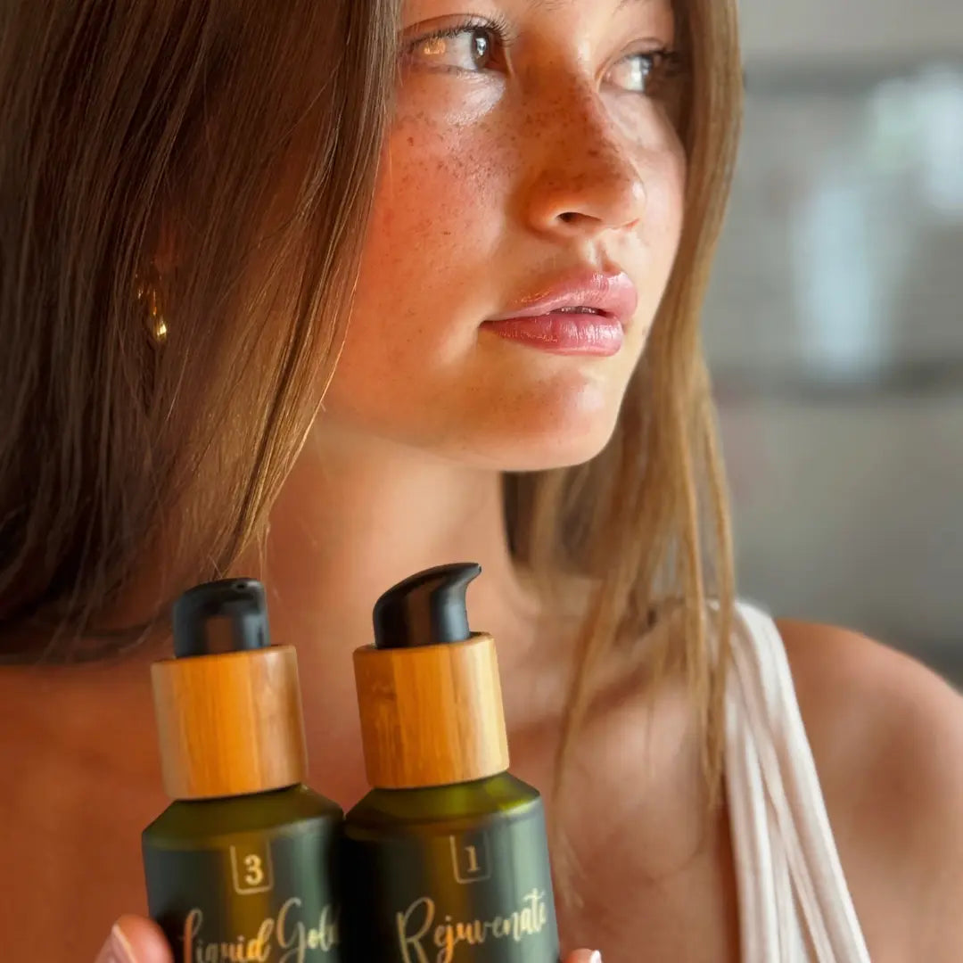 Woman holding two skincare bottles labeled 'Liquid Gold' and 'Rejuvenate'.