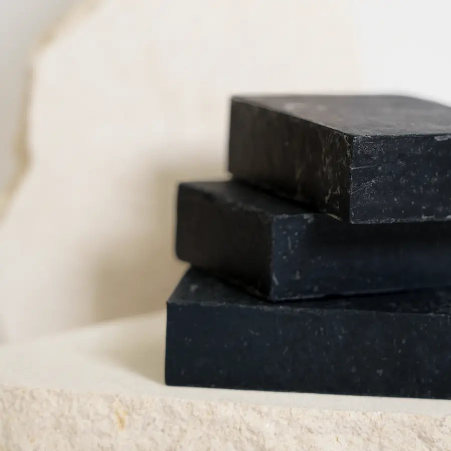 Stack of black soap bars on a beige surface