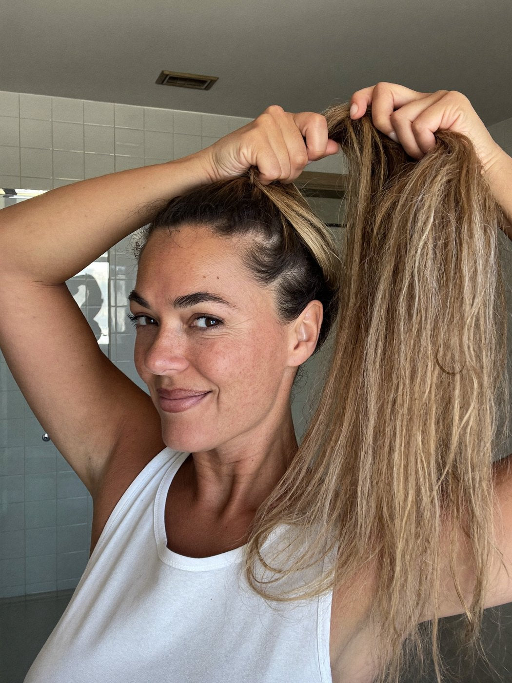 Woman gathering a thick, full ponytail in both hands